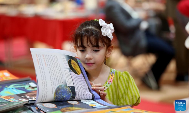 A girl reads a book at the 25th Baghdad International Book Fair in Baghdad, Iraq, on Sept. 17, 2024. (Photo: Xinhua)