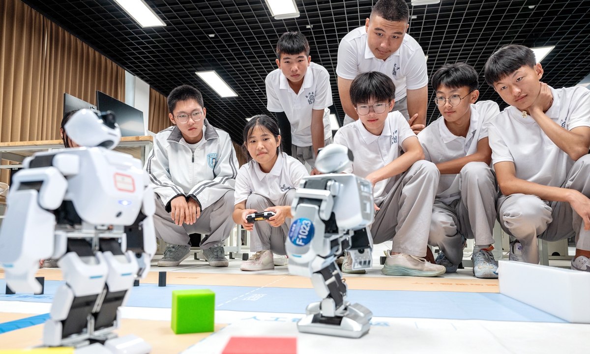 Students watch AI bipedal robots at a middle school in Changxing county, Huzhou, East China's Zhejiang Province, on September 19, 2024. The event, taking place amid this year's National Science Popularization Day activities that run from September 15 to 25, integrates various means such as a science fair and scientific experiments to allow students to engage with cutting-edge technology such as AI robots and drones. Photo: VCG