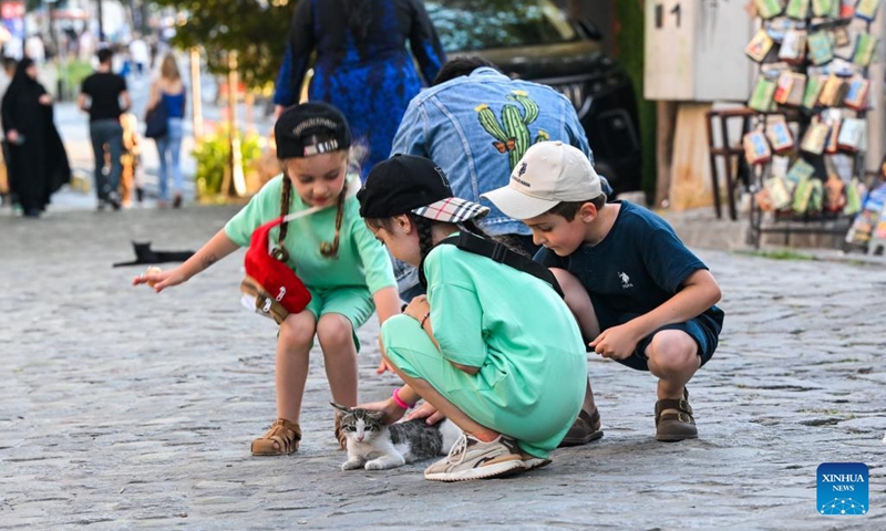 Children pet a stray cat on a street in Istanbul, Türkiye, June 30, 2024. Istanbul is known for its cat-loving tradition.  (Photo: Xinhua)