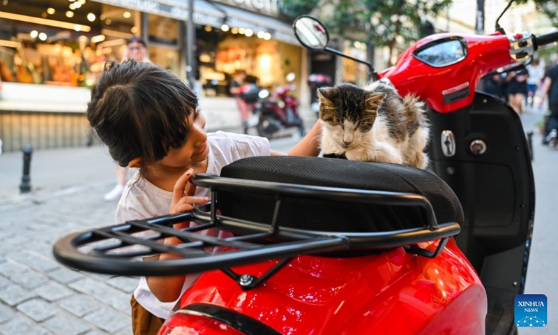 A child pets a stray cat resting on a motorcycle on a street in Istanbul, Türkiye, July 31, 2024. Istanbul is known for its cat-loving tradition.  (Photo: Xinhua)