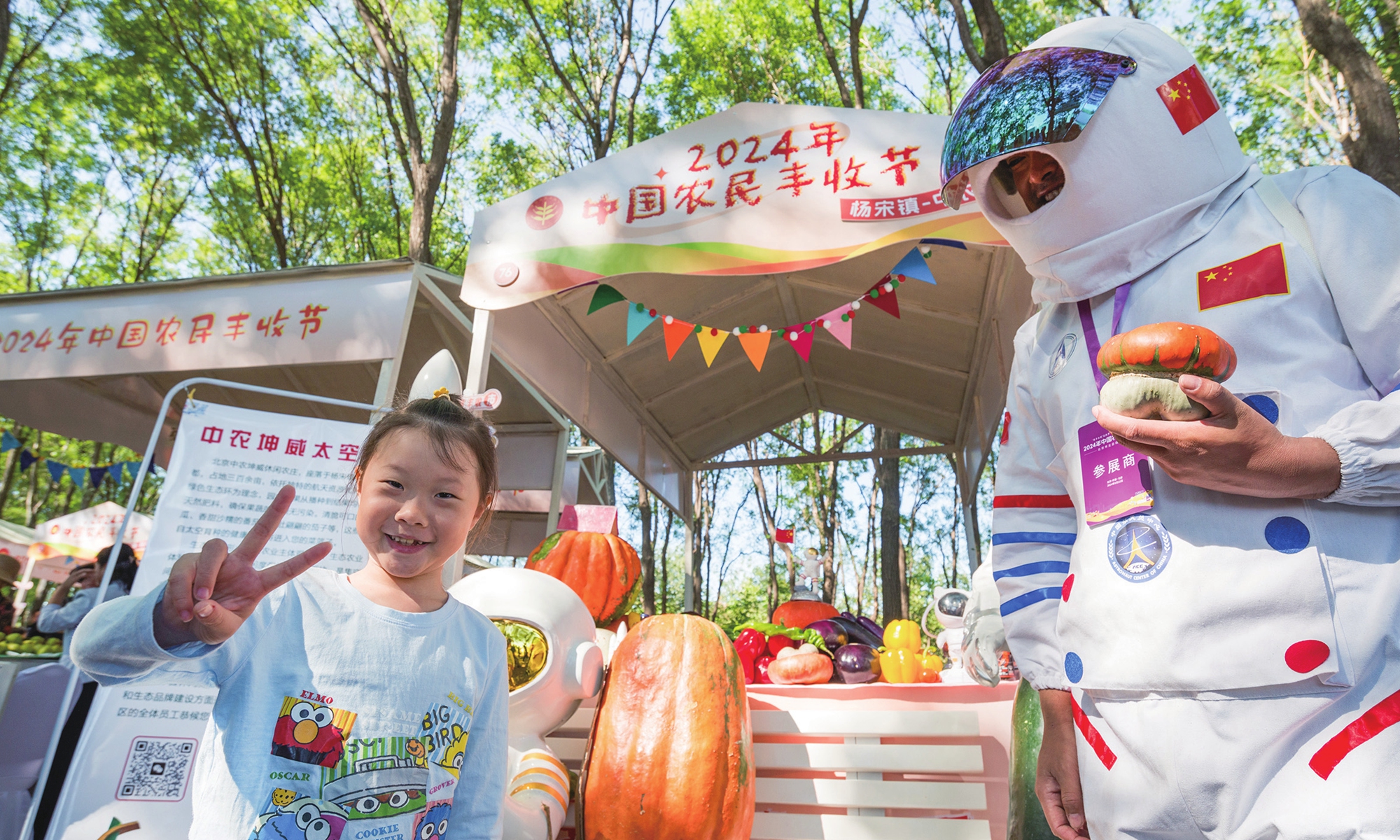 A child poses with an exhibitor whose company is displaying space-bred vegetables in the 7th Chinese Farmers' Harvest Festival held in Beijing on September 22, 2024. The event features more than 10 vibrant activities, including cultural performances, specialty agricultural markets and farming experiences. During the event, visitors can share the joy of farmers at harvest time while experiencing the charming rural culture. Photo: Chen Tao/GT