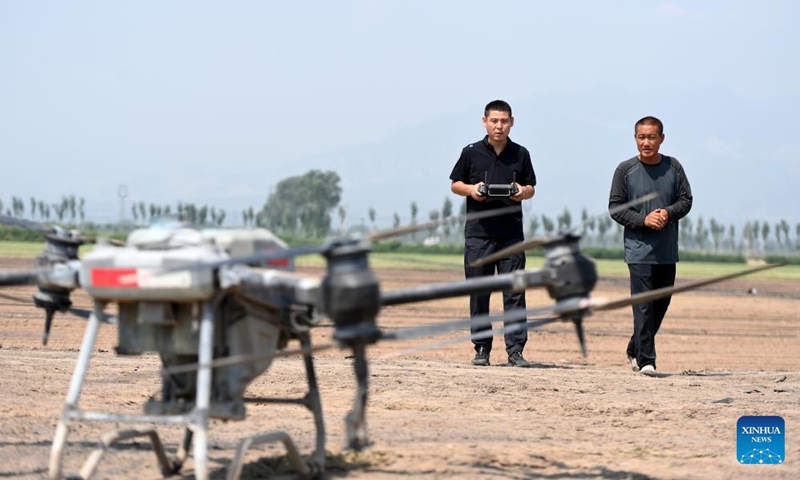 Zhao Yongzhuang (L) operates a drone to spray pesticide in a field in Beizhang Township, Wenshui County of north China's Shanxi Province, Aug. 20, 2024. Located in the eastern foot of Lyuliang mountains in Shanxi, Wenshui County is ideal for potato planting because of its large temperature difference between day and night. (Photo: Xinhua)