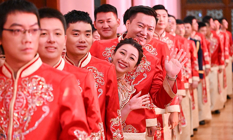 A bride and a bridegroom waves to camera at a group wedding site in Beijing on September 22, 2024.  A total of 5,000 Chinese couples tied the knot across 50 locations in China, marking the largest group wedding organized by Chinese authorities since the founding of the People's Republic of China. Photo: VCG