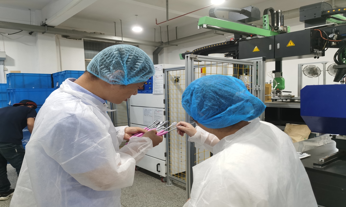 Tu Xinye (left), the manager of Shuguang Toothbrush Factory, checks whether the quality of the freshly produced toothbrushes on the production line is up to standard. Photo: Hu Yuwei/GT