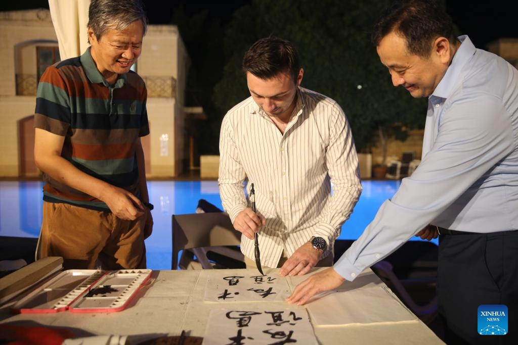 Pembroke Mayor Kaylon Zammit (C) writes Chinese calligraphy in Pembroke, Malta, Sept. 27, 2024. A Chinese culture night event was held on Friday evening in Pembroke, eastern Malta, drawing significant participation from the local community. The event showcased various aspects of Chinese culture, including traditional Chinese Medicine (TCM), Chinese calligraphy and painting, traditional music, and cuisine, alongside displays of exquisite Chinese handicrafts. (Photo: Xinhua)