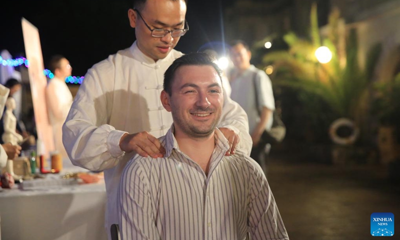 Pembroke Mayor Kaylon Zammit (front) experiences Chinese-style massage treatment in Pembroke, Malta, Sept. 27, 2024. A Chinese culture night event was held on Friday evening in Pembroke, eastern Malta, drawing significant participation from the local community. The event showcased various aspects of Chinese culture, including traditional Chinese Medicine (TCM), Chinese calligraphy and painting, traditional music, and cuisine, alongside displays of exquisite Chinese handicrafts. (Photo: Xinhua)