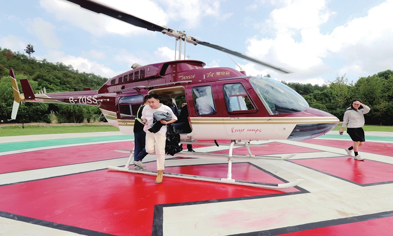 Tourists alight from a helicopter after an aerial tour of Xiazhu Lake National Wetland Park in Huzhou, East China's Zhejiang Province on September 29, 2024. The low-altitude excursion route has entered trial operation as the local county combines low-altitude journeys with cultural tourism. The scale of China's low-altitude economy is expected to surpass 2 trillion yuan ($285.24 billion) by 2030. Photo: VCG