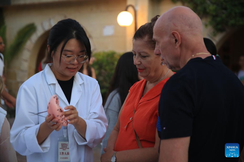 A Chinese doctor introduces traditional Chinese Medicine (TCM) to people in Pembroke, Malta, Sept. 27, 2024. A Chinese culture night event was held on Friday evening in Pembroke, eastern Malta, drawing significant participation from the local community. The event showcased various aspects of Chinese culture, including traditional Chinese Medicine (TCM), Chinese calligraphy and painting, traditional music, and cuisine, alongside displays of exquisite Chinese handicrafts. (Photo: Xinhua)