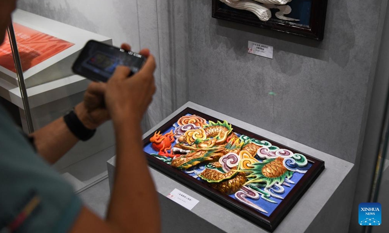 A visitor takes photos of an exhibit at the Hainan Intangible Cultural Heritage Exhibition Center in Haikou, south China's Hainan Province, Sept. 30, 2024. The exhibition center, one of the provincial capital's major public cultural projects, began trial operation on Monday and will last for one month. (Photo: Xinhua)