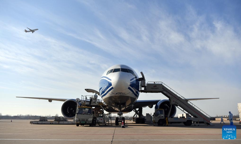 Airport staff members load a cargo plane at Xinzheng International Airport in Zhengzhou, central China's Henan Province, Dec. 30, 2021. Strategically positioned in central part of the country, Henan has been serving as a national hub of transporation for ages. The past decades saw the province building a modern transportation network consisting air flights, railways, highways, water channels and all sorts of ports. It is now rapidly extending its role to areas of cross-border logistics, investment, and trade to facilitate the dual circulation of domestic and international markets. Photo: Xinhua