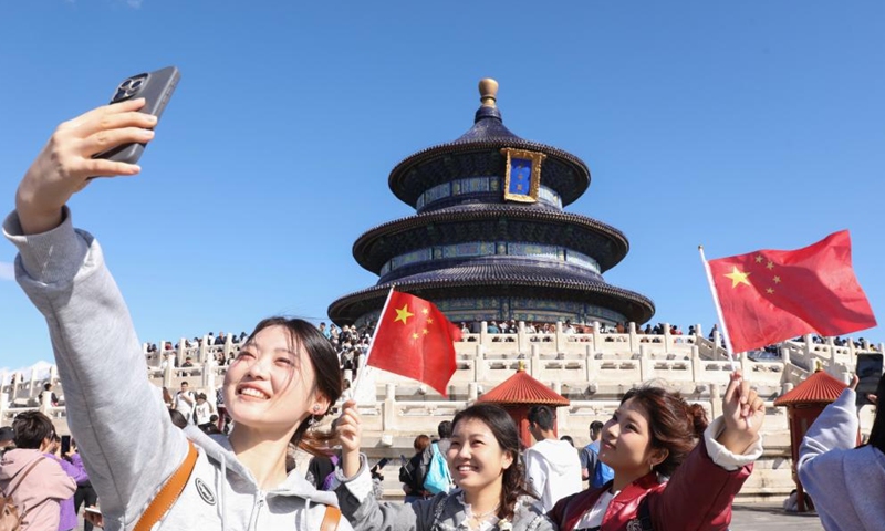 Tourists take selfies at Tiantan (Temple of Heaven) Park in Beijing, capital of China, Oct. 1, 2024. The National Day holiday period, which runs from Oct. 1 to Oct. 7 this year, is a peak travel and tourism season in China. (Photo by Chen Xiaogen/Xinhua)