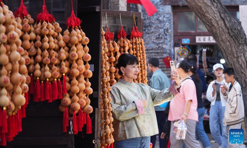 A visitor takes a selfie at an ancient trading compound of Zhoucun in Zibo, east China's Shandong Province, Oct. 1, 2024. The National Day holiday period, which runs from Oct. 1 to Oct. 7 this year, is a peak travel and tourism season in China. (Photo by Dong Naide/Xinhua)