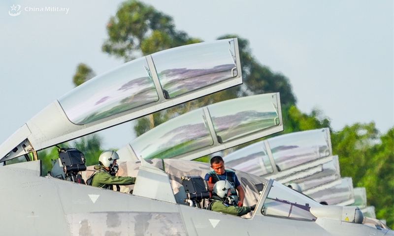 Pilots assigned to an aviation brigade with the air force under the Chinese PLA Southern Theater Command communicate with a ground crew member before take-off during a flight training exercise under complex meteorological conditions in early September, 2024. (eng.chinamil.com.cn/Photo by Zhao Yutong)