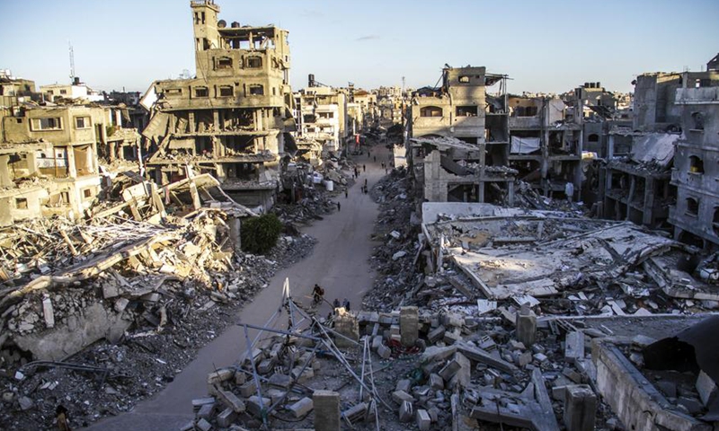 Palestinians are seen on a street between buildings destroyed in Israeli strikes in the northern Gaza Strip city of Jabalia, on Oct. 6, 2024. (Photo by Mahmoud Zaki/Xinhua)