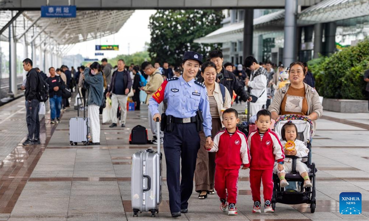 A policewoman helps passengers on the platform at Taizhou Railway Station in Taizhou, east China's Jiangsu Province, Oct. 6, 2024. China sees a surge in return trips on Sunday as the week-long National Day holiday draws to a close. (Photo: Xinhua)