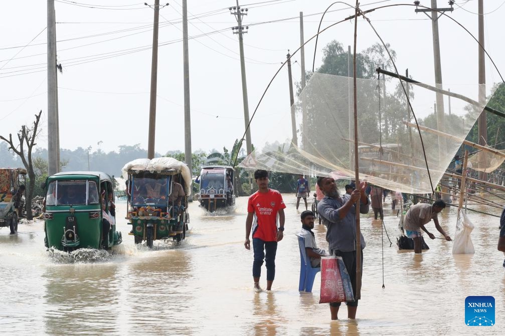 People wade through floodwater in Mymensingh, Bangladesh, Oct. 7, 2024. Days of devastating flash floods, triggered by heavy rains and upstream torrents, have stranded hundreds of thousands of people in Bangladesh's northern Mymensingh region, with thousands of homes still under water. (Photo: Xinhua)