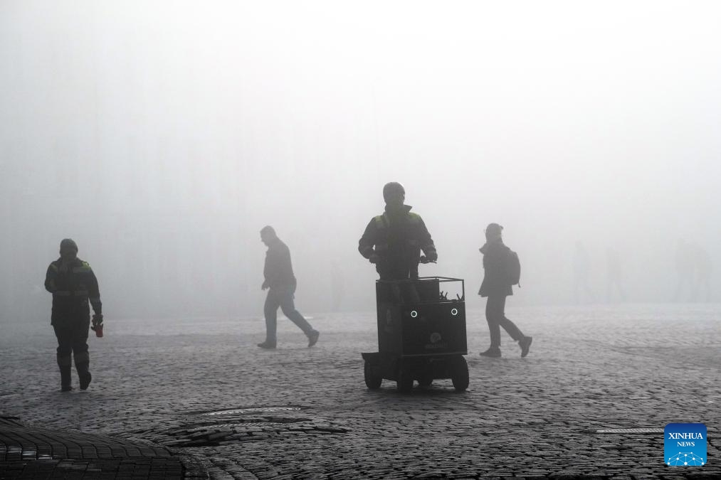 People walk at a square amid fog in Riga, Latvia, Oct. 8, 2024. (Photo: Xinhua)