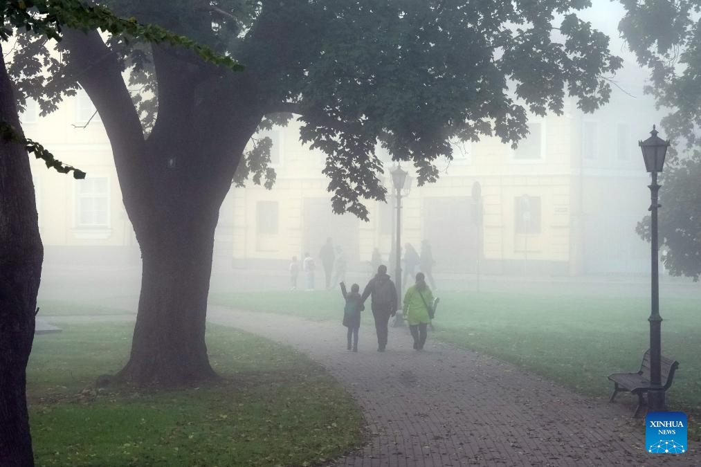 People walk at a park amid fog in Riga, Latvia, Oct. 8, 2024. (Photo: Xinhua)