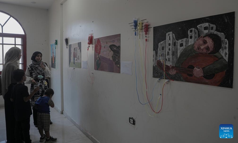 Palestinians attend a World Mental Health Day exhibition in the southern Gaza Strip city of Khan Younis, on Oct. 10, 2024. A total of 48 Palestinian children who received psychological treatment participated in the exhibition with their paintings. (Photo: Xinhua)