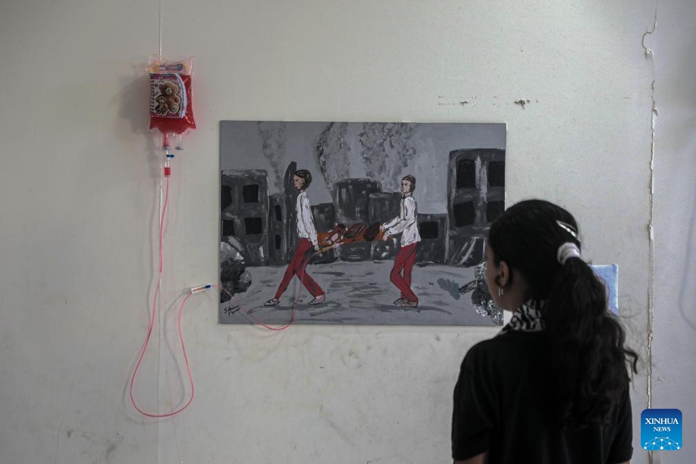 A Palestinian girl views an artwork at a World Mental Health Day exhibition in the southern Gaza Strip city of Khan Younis, on Oct. 10, 2024. A total of 48 Palestinian children who received psychological treatment participated in the exhibition with their paintings. (Photo: Xinhua)