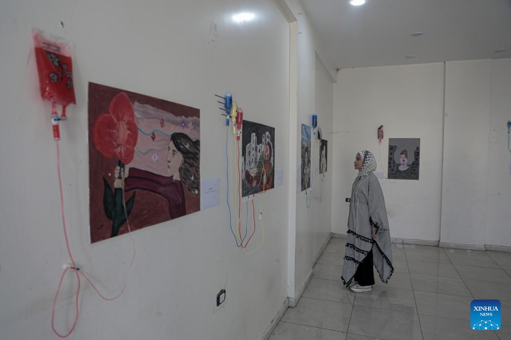 A Palestinian woman views an artwork at a World Mental Health Day exhibition in the southern Gaza Strip city of Khan Younis, on Oct. 10, 2024. A total of 48 Palestinian children who received psychological treatment participated in the exhibition with their paintings. (Photo: Xinhua)