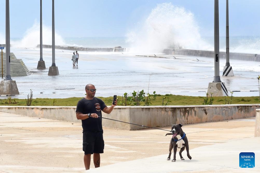 A man walks with his dog along a seaside road in Havana, Cuba, Oct. 9, 2024. Hurricane Milton brought intermittent rainfall to Cuba. (Photo: Xinhua)