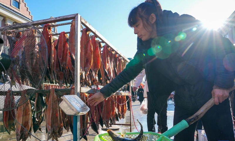 A fishmonger weighs a fish at Dongji fish market in Fuyuan City, northeast China's Heilongjiang Province, Oct. 11, 2024. (Photo: Xinhua)