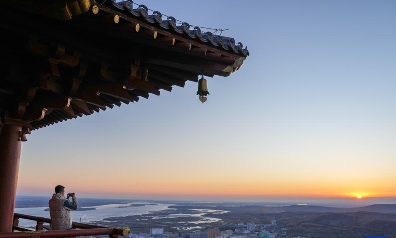 A tourist takes photos of the rising sun in Fuyuan City, northeast China's Heilongjiang Province, Oct. 12, 2024. Fuyuan City, a famous tourist attraction, has attracted over 2.1 million visitors from January to September this year. (Photo: Xinhua)