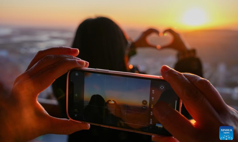 A tourist poses for photos with the rising sun in Fuyuan City, northeast China's Heilongjiang Province, Oct. 12, 2024. Fuyuan City, a famous tourist attraction, has attracted over 2.1 million visitors from January to September this year. (Photo: Xinhua)