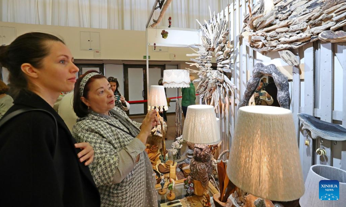 People visit the Belarusian Folk Crafts Exhibition in Minsk, Belarus, Oct. 12, 2024. The exhibition kicked off on Saturday in Minsk, where more than 200 masters of folk art presented their handmade ceramics and woodwork, jewelry and clothing, original dolls and toys, paintings, creative souvenirs and other items. The exhibition featured a variety of activities, including master classes in handicrafts, fashion shows and exhibitions of works by Belarusian designers, and attracted a large number of visitors. (Photo: Xinhua)