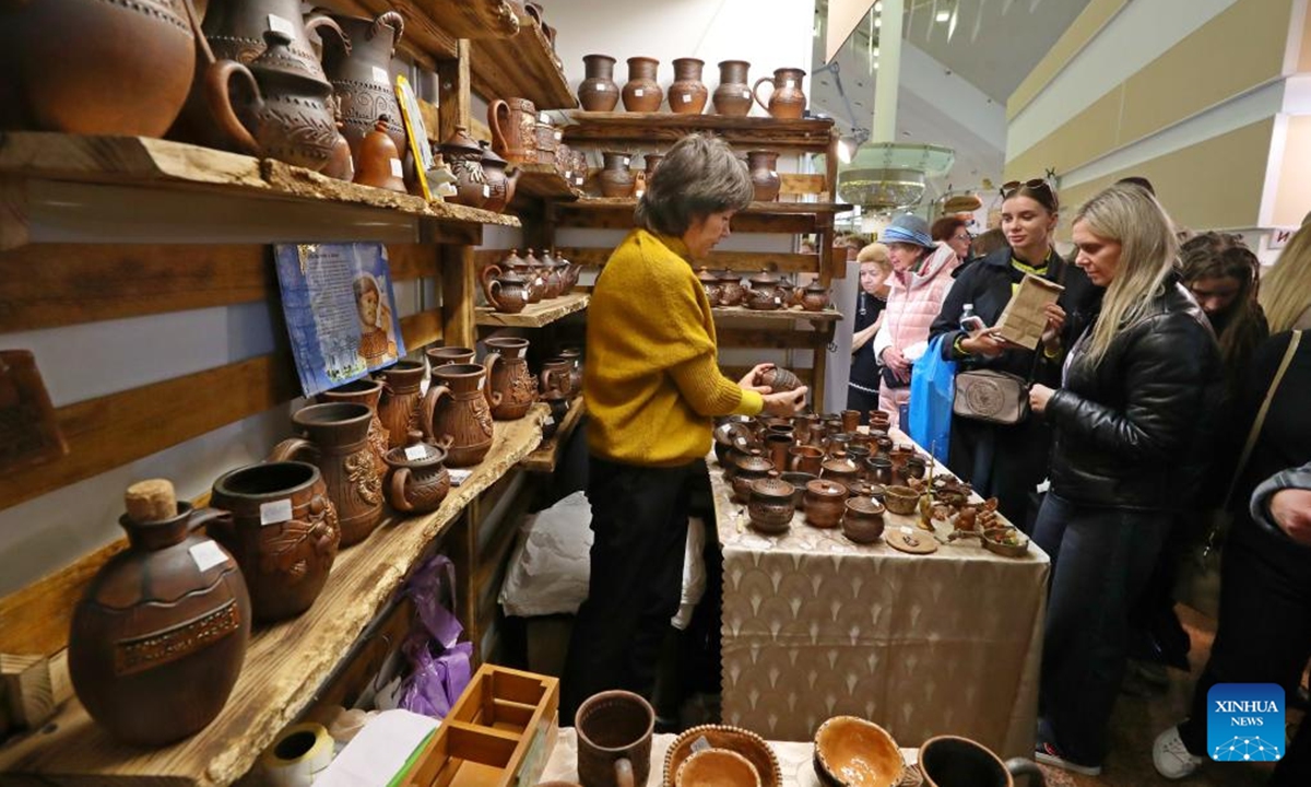 People visit the Belarusian Folk Crafts Exhibition in Minsk, Belarus, Oct. 12, 2024. The exhibition kicked off on Saturday in Minsk, where more than 200 masters of folk art presented their handmade ceramics and woodwork, jewelry and clothing, original dolls and toys, paintings, creative souvenirs and other items. The exhibition featured a variety of activities, including master classes in handicrafts, fashion shows and exhibitions of works by Belarusian designers, and attracted a large number of visitors. (Photo: Xinhua)