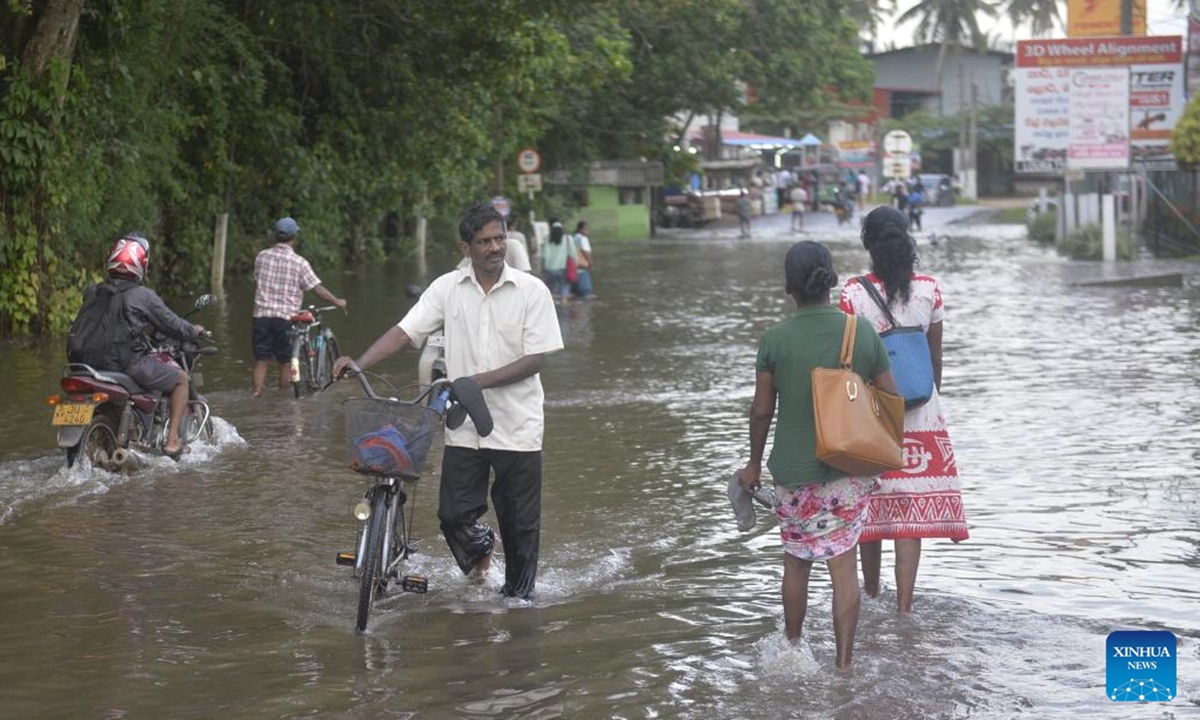 People walk in a flooded street in Minuwangoda, Sri Lanka, on Oct. 12, 2024. Sri Lankan president Anura Kumara Dissanayake has instructed officials to provide immediate relief to people affected by recent adverse weather conditions across the country, the President's Media Division (PMD) said on Saturday. (Photo: Xinhua)