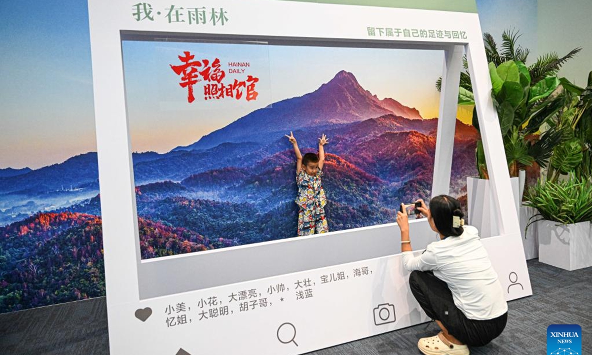 A visitor poses for a photo at the Guarding Rainforest Homeland exhibition in Haikou, south China's Hainan Province, Oct. 13, 2024. The Guarding Rainforest Homeland exhibition has been held by the management office of the National Park of Hainan Tropical Rainforest in Haikou. Featuring animal specimens, photographs and videos, the exhibition showcases the beauty of rainforest and introduces the construction process of the National Park of Hainan Tropical Rainforest. (Photo: Xinhua)