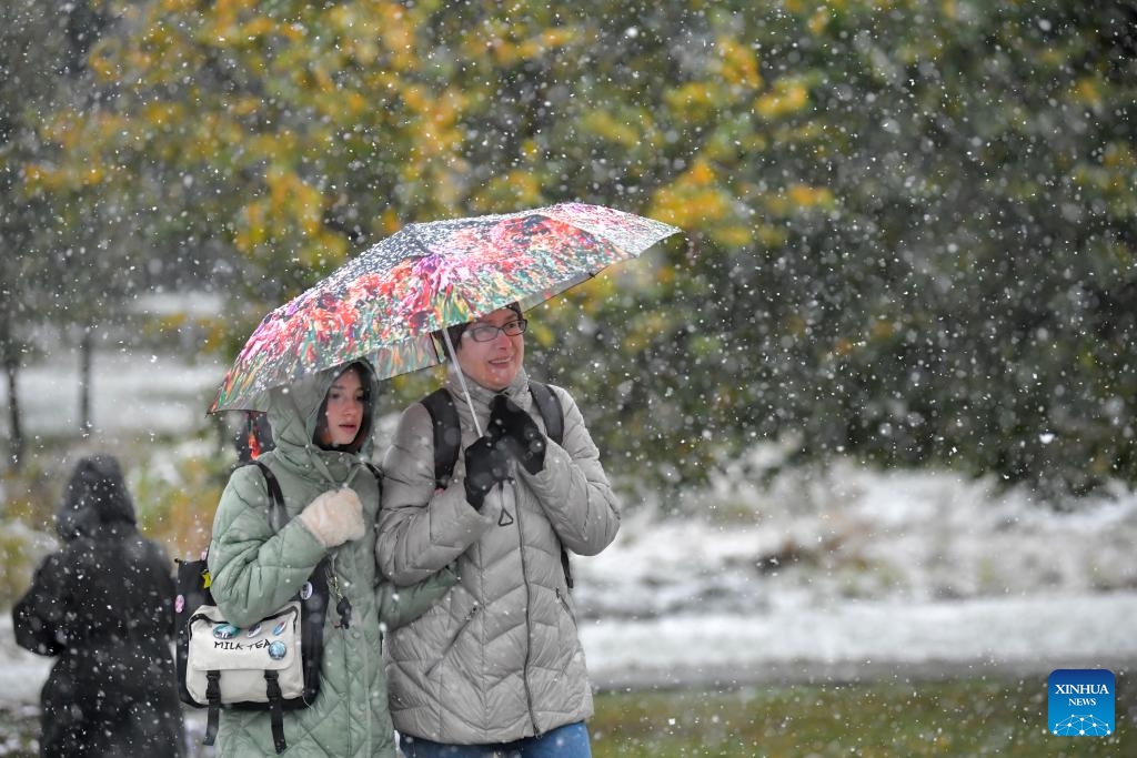 People walk with umbrellas during snowfall in Moscow, Russia, on Oct. 14, 2024. (Photo: Xinhua)