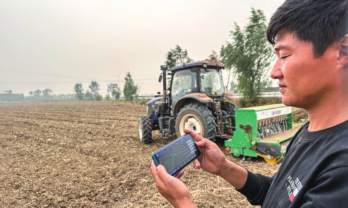 A farmer remotely controls a drone seeder equipped with the BeiDou Navigation Satellite System to sow winter wheat on a farm in Anyang county, Central China's Henan Province on October 15, 2024. The use of unmanned agricultural machinery not only increases the speed of sowing but also ensures the consistency and accuracy of seeding. Photo: VCG