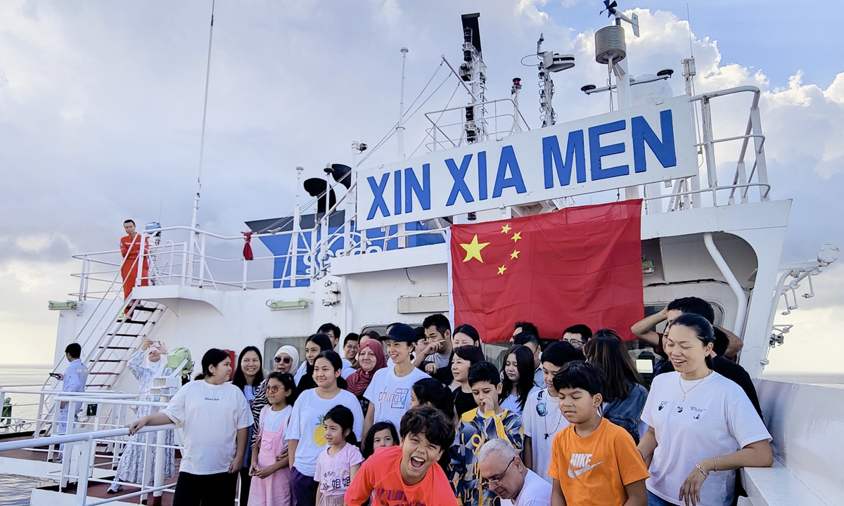 Chinese evacuees and their family members smile and take a photo with the vessel Xin Xiamen upon arrival on October 1, 2024. Photo: Courtesy of China COSCO Shipping Corporation