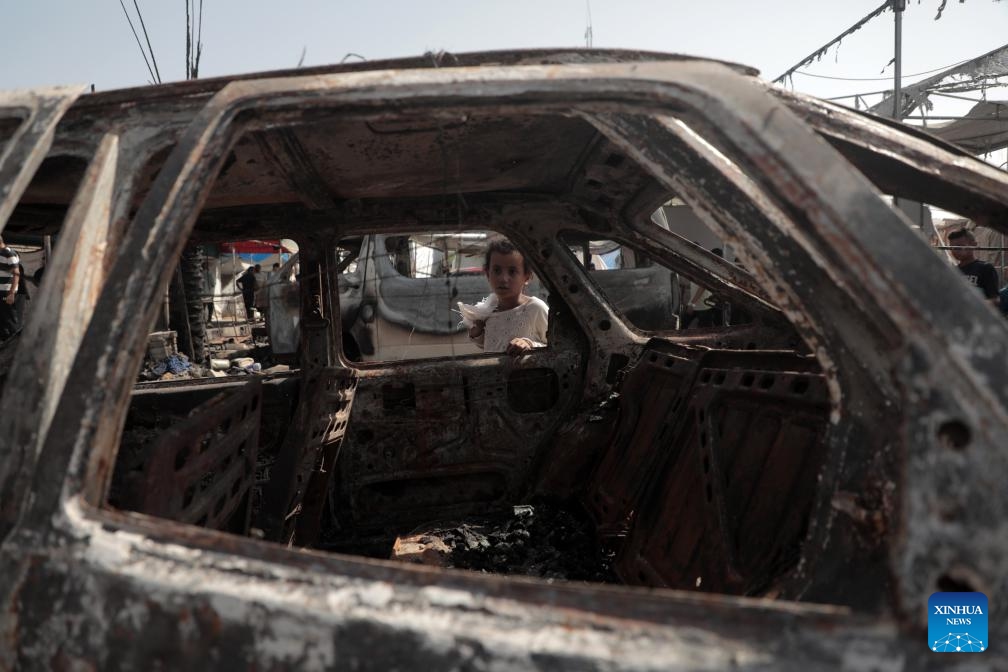 A Palestinian child is seen near a damaged car after an Israeli airstrike in the city of Deir al-Balah in the central Gaza Strip, on Oct. 14, 2024. At least three Palestinians were killed on Monday in an Israeli airstrike that targeted the tents of displaced persons in Deir al-Balah, located in the central Gaza Strip, according to Palestinian sources. (Photo: Xinhua)