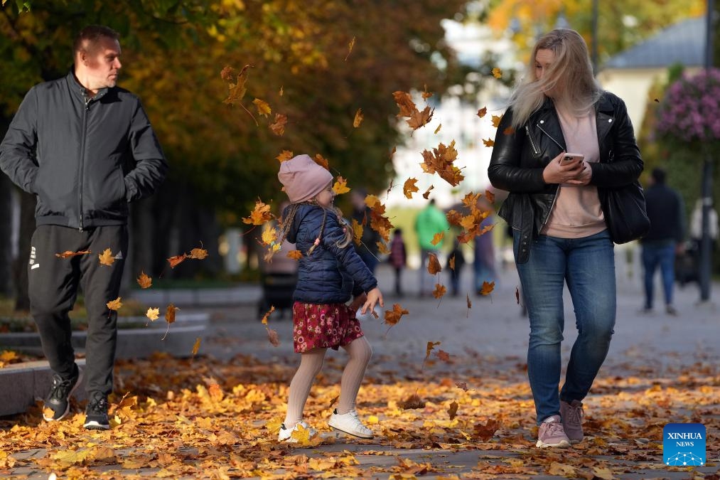 People enjoy the autumn scenery in Ogre, Latvia, Oct. 13, 2024. (Photo: Xinhua)