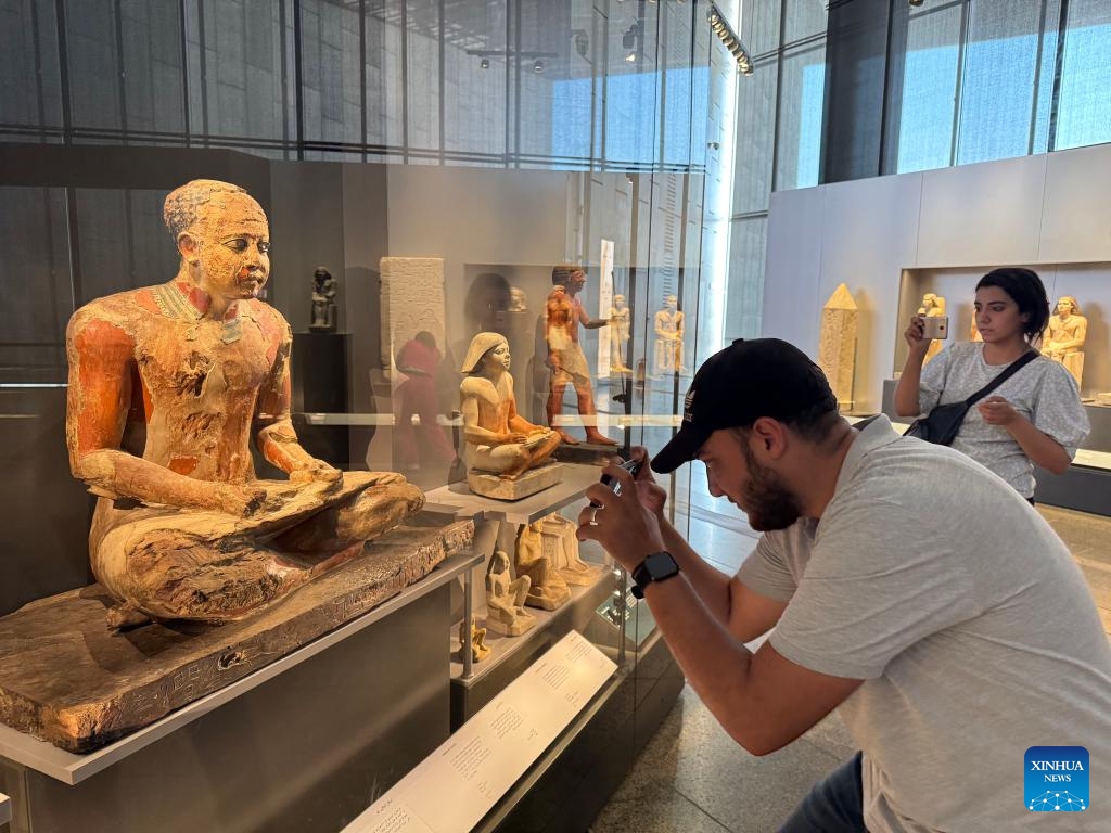 Visitors take photos of exhibits at an exhibition hall of the Grand Egyptian Museum in Giza, Egypt, Oct. 15, 2024. The Grand Egyptian Museum on Tuesday announced trial operations of its Main Galleries, starting from Oct. 16, 2024, offering visitors an exclusive preview of twelve exhibition halls with artifacts spanning from prehistoric times to the Roman era. (Photo: Xinhua)