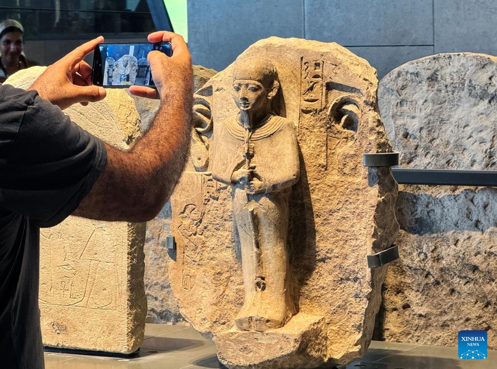 A visitor takes photos of exhibits at an exhibition hall of the Grand Egyptian Museum in Giza, Egypt, Oct. 15, 2024. The Grand Egyptian Museum on Tuesday announced trial operations of its Main Galleries, starting from Oct. 16, 2024, offering visitors an exclusive preview of twelve exhibition halls with artifacts spanning from prehistoric times to the Roman era. (Photo: Xinhua)