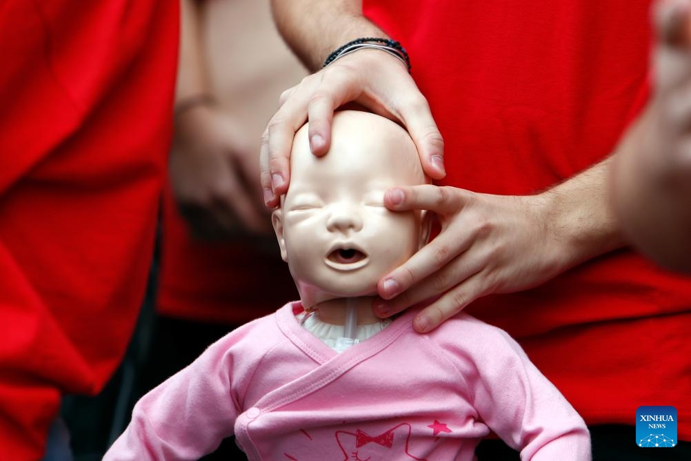 A Romanian Red Cross volunteer holds a medical mannequin while preparing to perform resuscitation maneuvers during a flash mob to mark the World Restart a Heart Day in central Bucharest, Romania, Oct. 16, 2024. World Restart a Heart Day, celebrated on Oct. 16, is aimed at raising awareness of cardiopulmonary resuscitation and defibrillation in saving lives. (Photo:Xinhua)