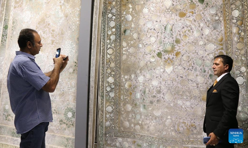 A man poses for photos in front of a product during the 16th International Floor Coverings, Moquette, Machine-Made Carpet and Related Industries Exhibition in Tehran, Iran, Oct. 17, 2024. The exhibition was held in Tehran from Monday to Thursday. (Photo: Xinhua)