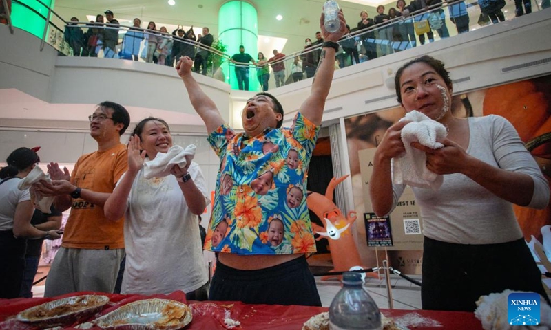 A contestant raises arms to celebrate his winning at the pumpkin pie eating contest at Metrotown Shopping Mall in Burnaby, British Columbia, Canada, Oct. 19, 2024.

The competition required participants to finish as much of a 2-pound pie as possible in 5 minutes without using their hands. (Photo: Xinhua)