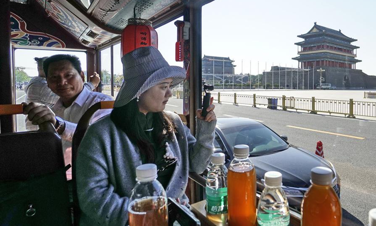 Tourists ride in a refurbished antique bus called dang dang che during a sightseeing tour along the Central Axis in Beijing, capital of China, Oct. 15, 2024. (Photo: Xinhua)