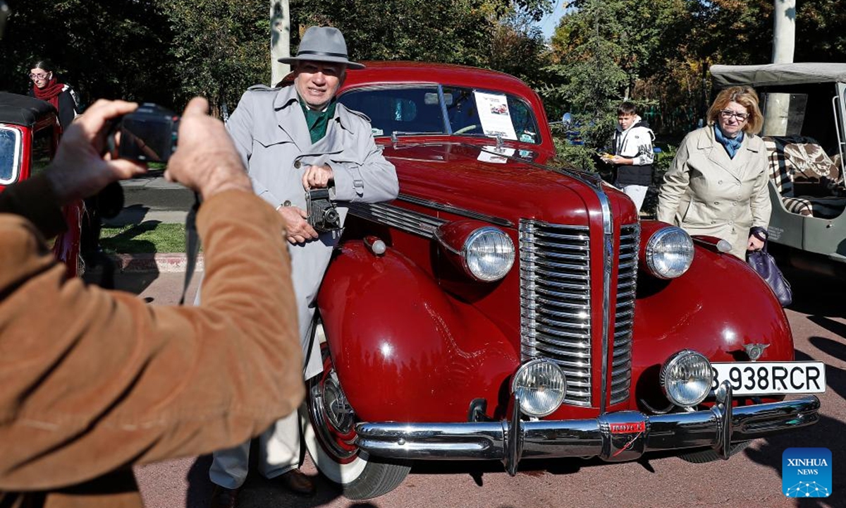 A man poses for photos by a Buick 40 Special vintage car during the Autumn Retro Parade in Bucharest, Romania, Oct. 20, 2024.   (Photo: Xinhua)