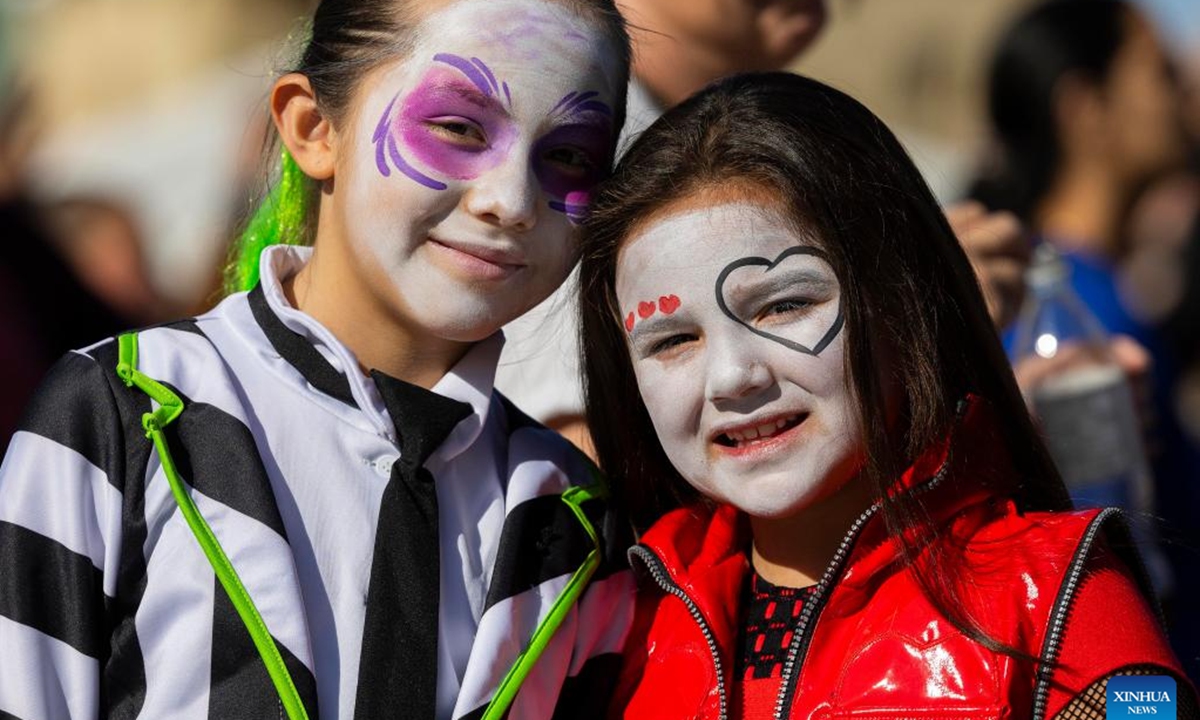 Girls with face paintings pose for photos during Celebration Scare, a family-friendly Halloween bash held in Mississauga, Ontario, Canada, on Oct. 19, 2024.  (Photo: Xinhua)