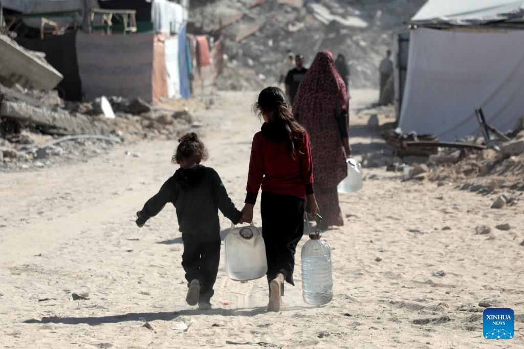 Palestinian children return home after filling bottles with water from a vehicle distributing free water, in the southern Gaza Strip city of Khan Younis, on Oct. 20, 2024. (Photo: Xinhua)