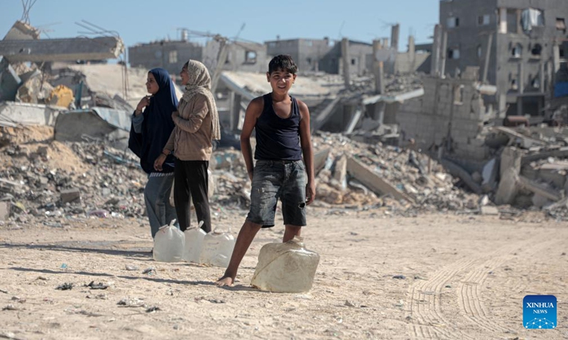 A Palestinian child returns home after filling bottles with water from a vehicle distributing free water, in the southern Gaza Strip city of Khan Younis, on Oct. 20, 2024. (Photo: Xinhua)