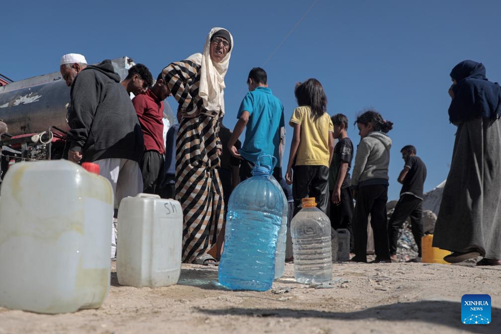 Palestinians fill bottles with water from a vehicle distributing free water in the city of Khan Younis in the southern Gaza Strip, on Oct. 20, 2024. (Photo: Xinhua)