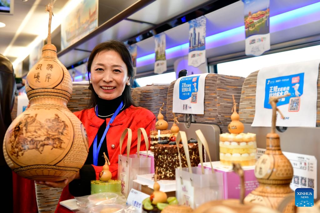 Liu Wei, an intangible cultural heritage inheritor, displays a calabash on the train G9227, the first train of the Weifang-Yantai high-speed railway in east China's Shandong Province, Oct. 21, 2024. The Weifang-Yantai high-speed railway was put into operation on Monday, increasing the total operational length of high-speed railway in Shandong to 3,047 kilometers. (Photo: Xinhua)